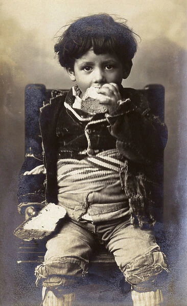 A poor young boy tucking into a hunk of bread - Italy