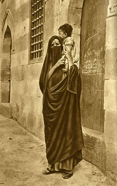 Woman in face veil with child on her shoulder, Cairo, Egypt