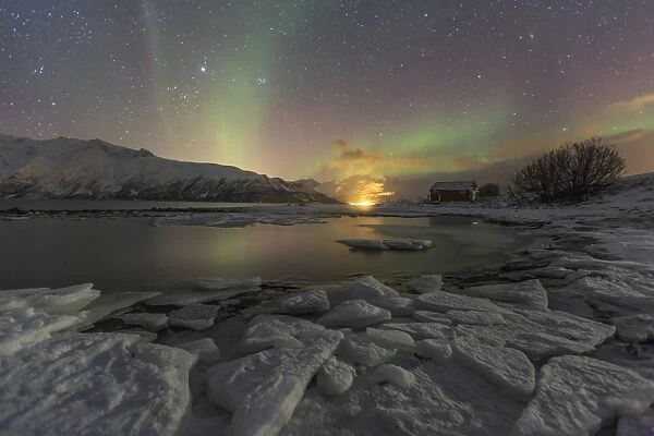 The Northern Lights illuminates the icy landscape in Svensby, Lyngen Alps, Troms