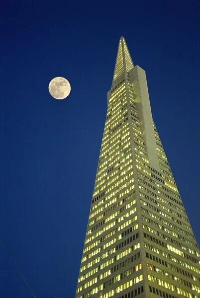 The Transamerica Pyramid, illuminated at dusk with full moon, designed by the architect William Pereira and built in 1972, San Francisco, California, United States of America