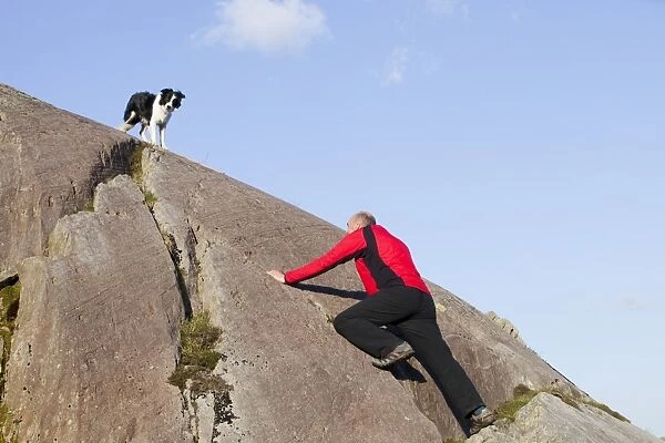 A climber and Border Collie dog on a boulder above Chapel Stile in the Langdale Valley in the Lake district