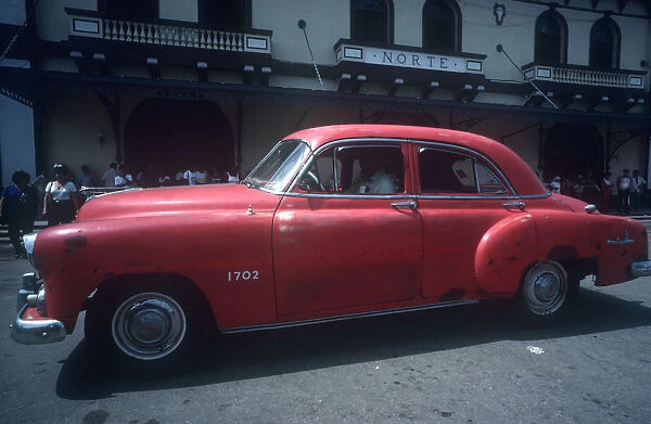 20024484. CUBA Ciego de Avila Moron Red 1950s car being driven in the street