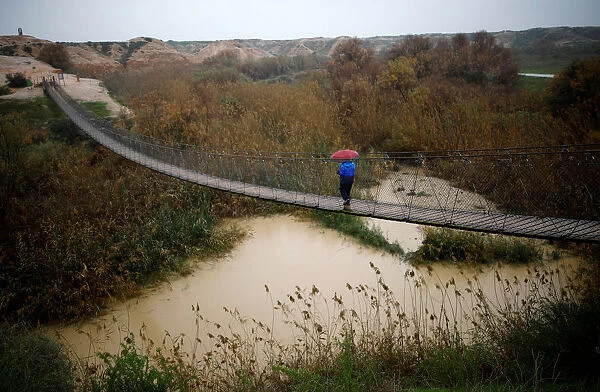A man walks on a bridge crossing over the Besor stream on a rainy day