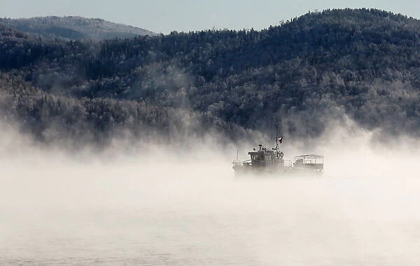 A motorboat travels along the Yenisei River in the Siberian Taiga area as the air
