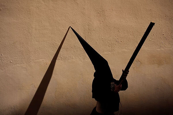 A penitent takes part in the Santa Cruz brotherhood procession during Holy Week in Malaga