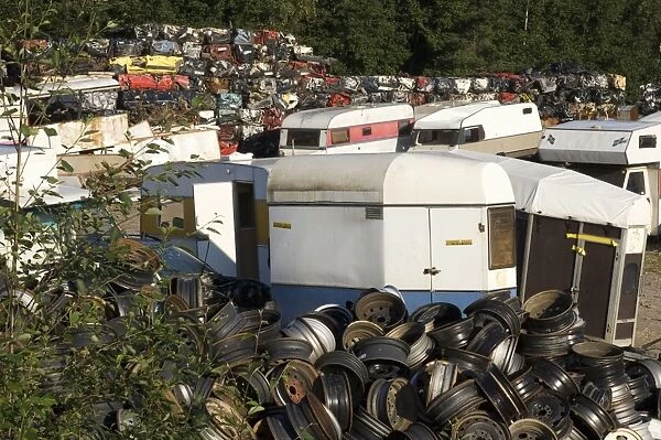 Scrapyard with wheel hubs, caravans and crushed cars, Sweden