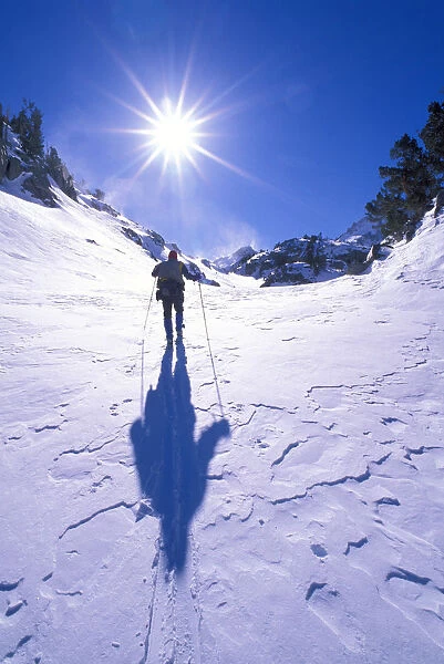 Backcountry skier crossing wind blown snow near Treasure Lakes, John Muir Wilderness