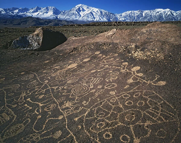 USA, California, Bishop. Curvilinear abstract-style petroglyphs and Eastern Sierra Mountains