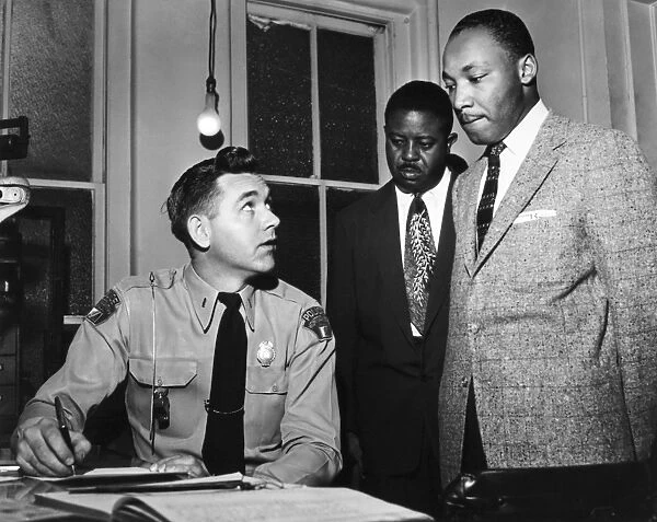 (1929-1968). American cleric and civil rights leader. King (right) being booked by Lieutenant Drue H. Lackey of the Montgomery, Alabama, Police Department, for his role in leading a boycott of segregated city buses, 23 February 1956. At his side is Ralph David Abernathy, another leader of the bus boycott