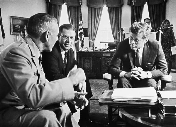 35th President of the United States. Being briefed on the situation in South Vietnam by General Maxwell Taylor, Chairman of the Joint Chiefs of Staff (left), and Robert McNamara, Secretary of Defense (center), in the Oval Office of the White House, Washington, D. C. 2 October 1963