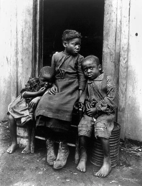 AFRICAN AMERICAN CHILDREN. Three African American children seated in a doorway