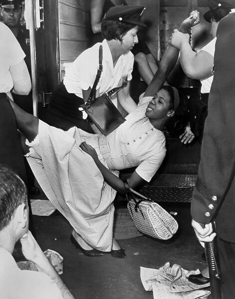 African American woman being carried to a police wagon during a Civil Rights demonstration in Brooklyn, New York. Photographed by Dick DeMarsico, 1963