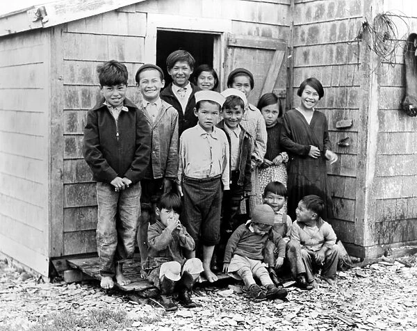 ALASKA: ALEUTIAN ISLANDS. A group of Aleutian children posing in front of a house