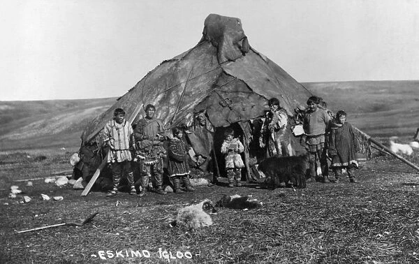 ALASKA: ESKIMO IGLOO. A group of Eskimos standing in front of their igloo in Alaska