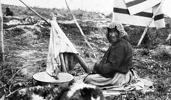 ALASKA: ESKIMO WOMAN. An Eskimo woman sitting outside cleaning hair off of a hide, Nome, Alaska