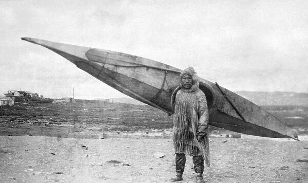 ALASKA: KAYAKING. An Eskimo man carrying a kayak in Nome, Alaska