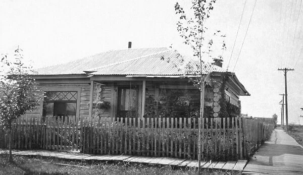 ALASKA: LOG CABIN. A log cabin on a residential corner with a wooden plank sidewalk in Fairbanks