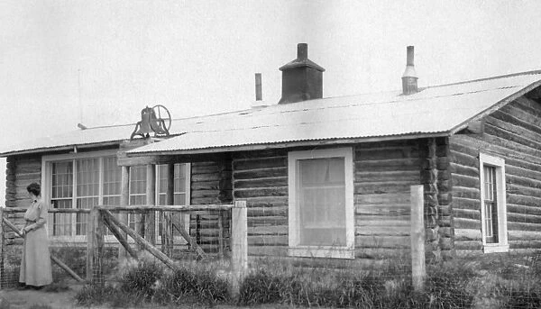 ALASKA: LOG CABIN. A woman standing in front of a log cabin in Fairbanks, Alaska