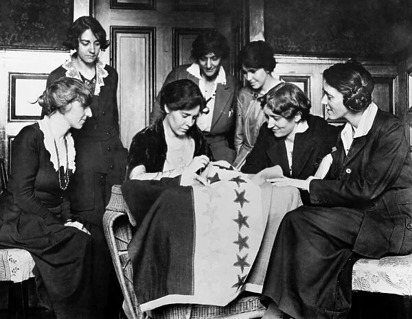 ALICE PAUL (1885-1977). American social reformer. Fellow suffragettes watch Alice Paul sewing another star on the suffragette flag, c1912-1920