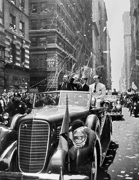 American industrialist, aviator, and film producer. Waving to crowds during a ticker tape parade up Broadway in New York City, 15 July 1938, one day after completing his flight around the world. Next to him are Grover Whalen, President of the New York Worlds Fair (left), and Al Lodwick, Hughes flight manager and press agent