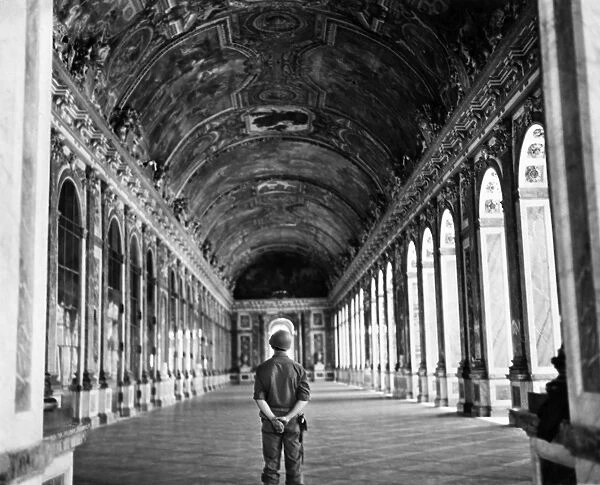 An American soldier standing in the Hall of Mirrors at the palace of Versailles, France, following its liberation by the Allies during World War II. Photograph by Burt Brandt, August 1944