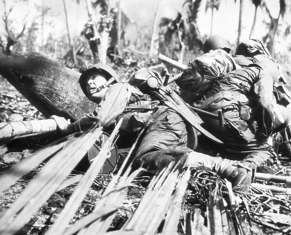 American soldiers, part of the first wave to land on Leyte Island, Philippines, take cover from Japanese machine gun fire. October 1943