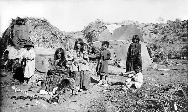 APACHE GROUP, c1909. A group of Apache women and children in front of their thatched huts