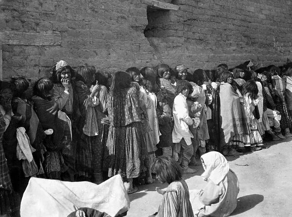 APACHE RESERVATION, c1899. Line of Apache men, women and children wait for rations