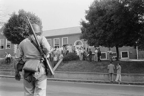 An armed National Guardsman observes as a group of the first black students are admitted to Clinton High School in Clinton, Tennessee, 1 September 1956