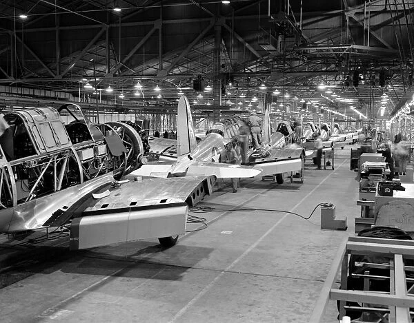 Assembly line production of BT-13A Valiant basic trainer aircraft at a Vultee factory in Downey, California, during World War II. Photographed by Alfred T. Palmer, c1942
