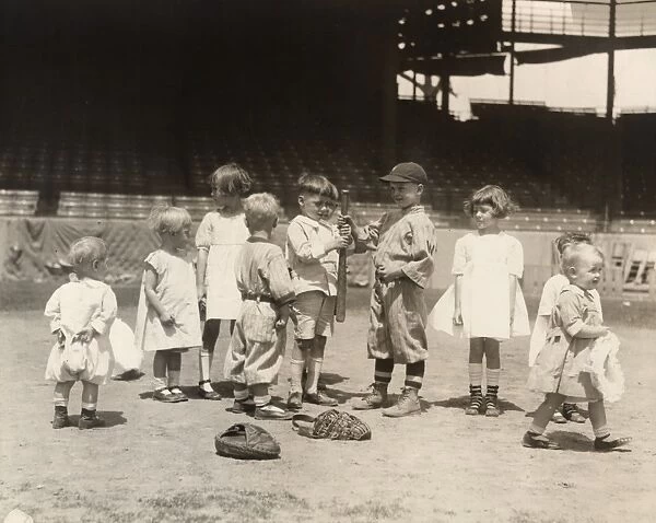 BASEBALL: BOYS AND GIRLS. Young boys and girls on a baseball field at a major league stadium. Photograph, early 20th century