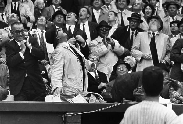 BASEBALL CROWD, 1962. President John F. Kennedy ducks out of sight (right, behind ball player) as a foul ball hit by Willie Tasby came towards him during a game between the Washington Senators and the Detroit Tigers, 9 April 1962. At right, just behind the president, is Secretary of the Treasury Douglas Dillon. At far left is Vice President Lyndon Johnson