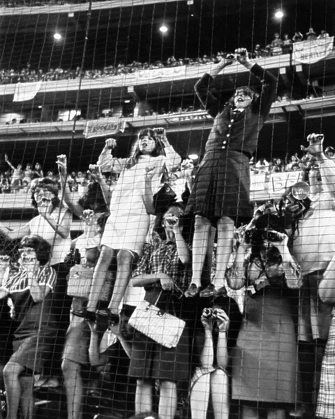 THE BEATLES, 1965. Fans climbing a fence at The Beatles concert at Shea Stadium in New York City