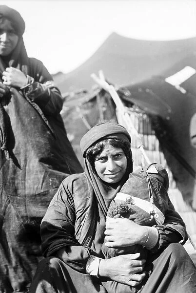 BEDOUIN WOMEN. Portrait of a Bedouin woman with a baby at a camp in the Middle East