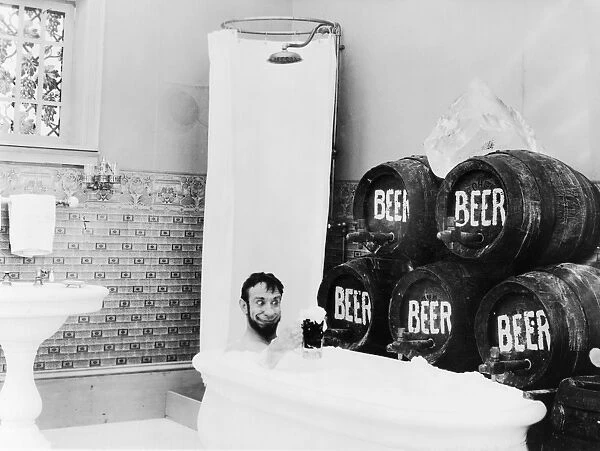 BEER, c1916. A man in a bathtub holding a glass of beer next to several barrels of beer