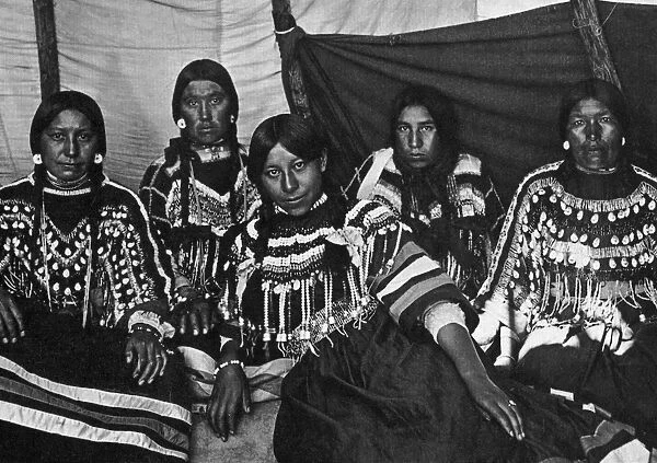 BLACKFOOT WOMEN, c1907. Five Blackfoot women wearing clothing decorated with beads and cowrie shells. Photograph by Norman Fosyth, c1907