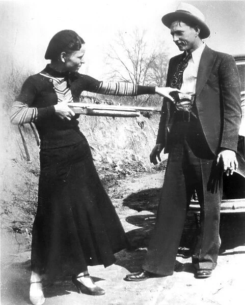BONNIE AND CLYDE, 1933. American criminal Bonnie Parker (1911-1934) playing at holding up her partner, Clyde Barrow (1909-1934). Photographed in 1933