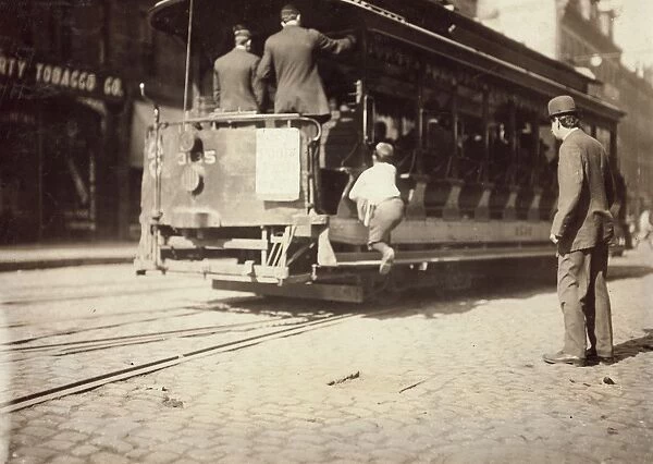 BOSTON: NEWSBOY, 1909. A newsboy flipping cars, on a trolley in Boston, Massachusetts