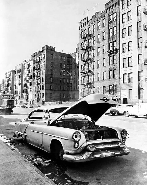 BRONX: ABANDONED CAR, c1964. An abandoned car stripped for parts on Macombs Road in the Bronx