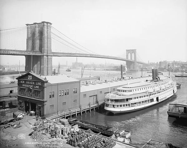 BROOKLYN BRIDGE, c1905. Steamboat parked at a marine terminal next to the Brooklyn Bridge