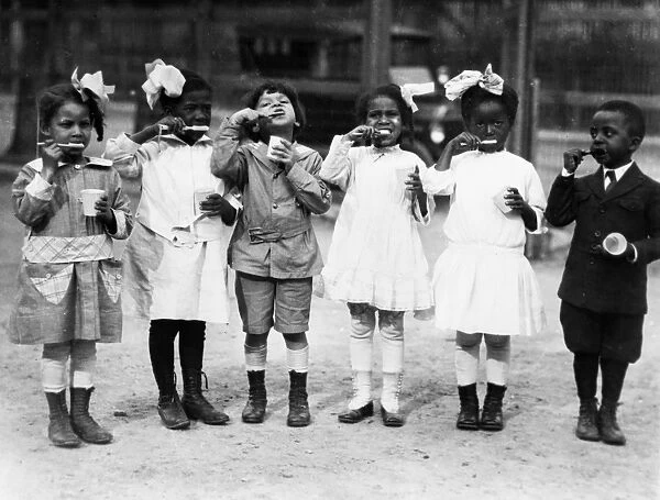 BRUSHING TEETH, c1910. First graders brushing their teeth outside of school in Washington, D