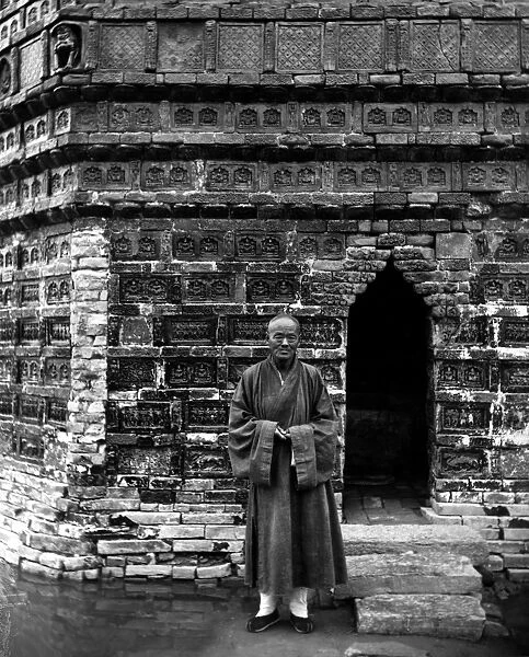 A Buddhist monk standing outside the entrance of the Iron Pagoda, built in the mid-11th century, at the Youguo monastery in Kaifeng, China. Photographed c1912