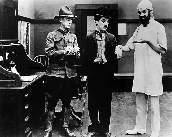 CHAPLIN: SHOULDER ARMS. Charlie Chaplin, center, undergoing a medical examination in his World War I film Shoulder Arms, 1918