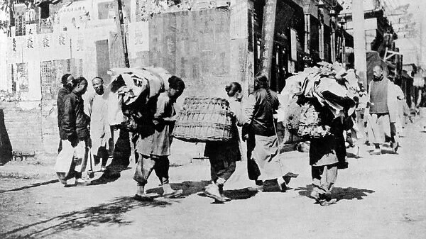 CHINA: RAG-PICKERS, c1920. Rag-pickers carrying bundles of rags down the street in China