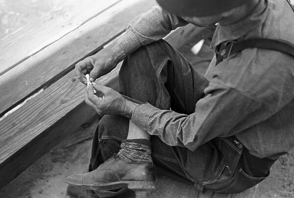 CIGARETTE ROLLING, 1938. A farmer hand rolling a cigarette, Irwinville Farms, Georgia