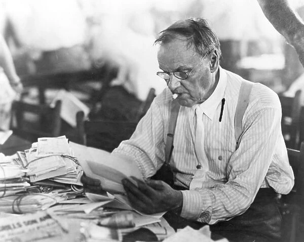CLARENCE DARROW (1857-1938). American lawyer; reading his mail during a lull in