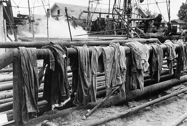 Clothing of oil drilling workers drying on a steam pipe in Kilgore, Texas. Photograph by Russell Lee, April 1939