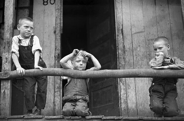 COAL MINERs BOYS, 1938. Three sons of a coal miner leaning on a rustic porch railing
