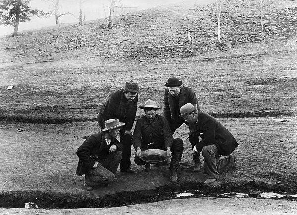 COLORADO: GOLD MINING, 1891. A group of men watching a placer miner panning for