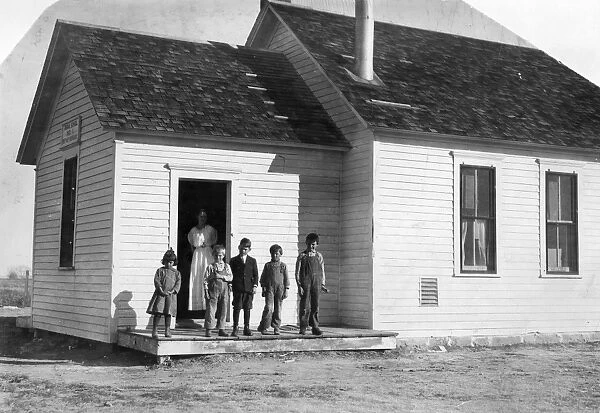 COLORADO SCHOOLHOUSE, 1915. Five pupils and their teacher outside a one room schoolhouse